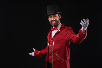 Photo of Portrait of showman in red costume and hat on black background, space for text