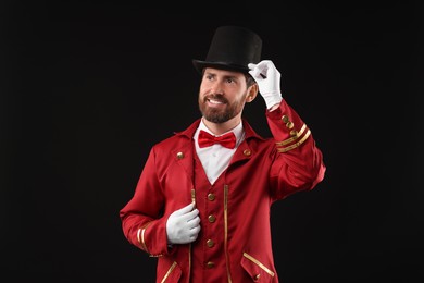 Photo of Portrait of showman in red costume and hat on black background