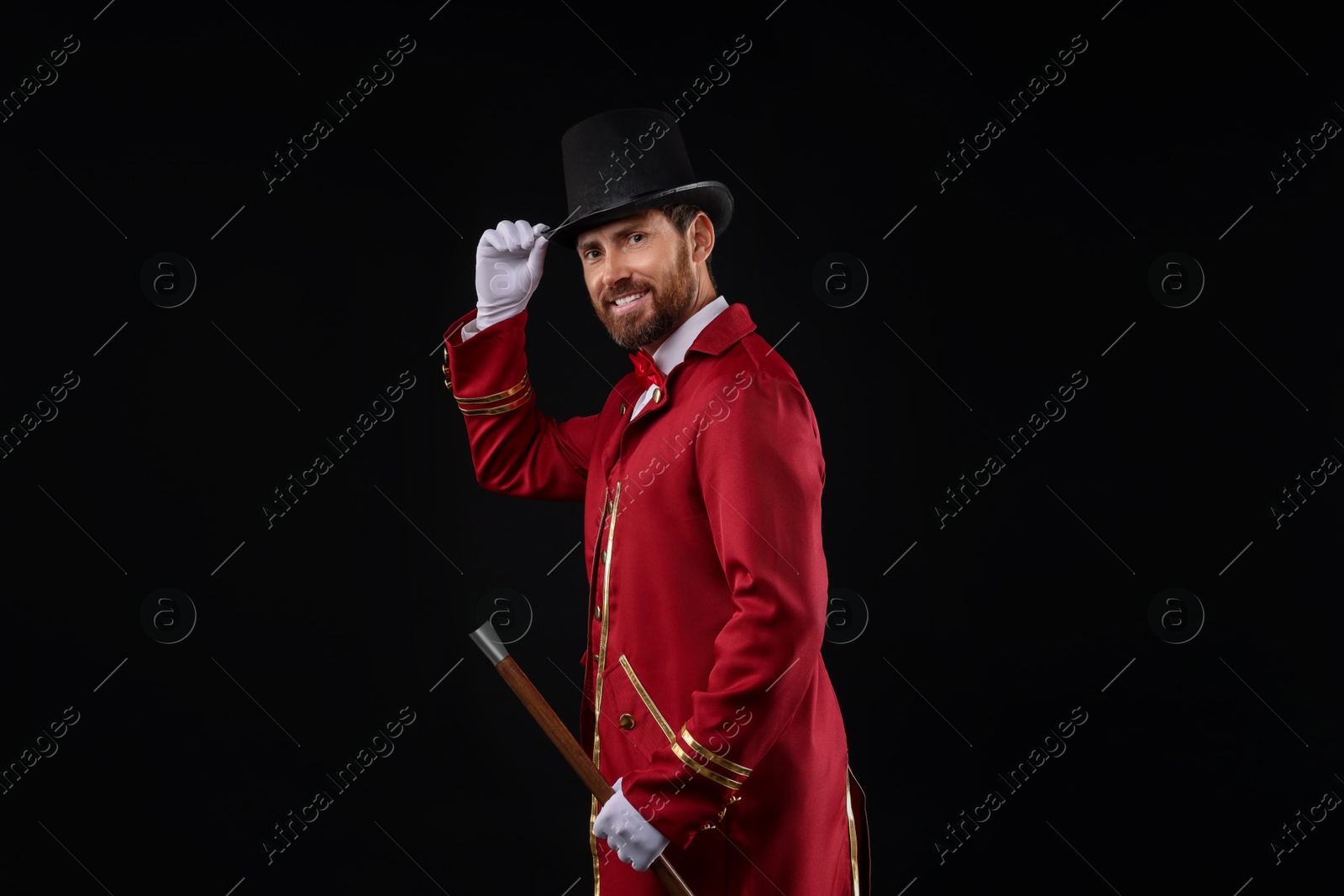 Photo of Portrait of showman in red costume and hat on black background