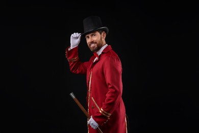 Photo of Portrait of showman in red costume and hat on black background