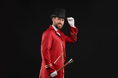 Photo of Portrait of showman in red costume and hat on black background