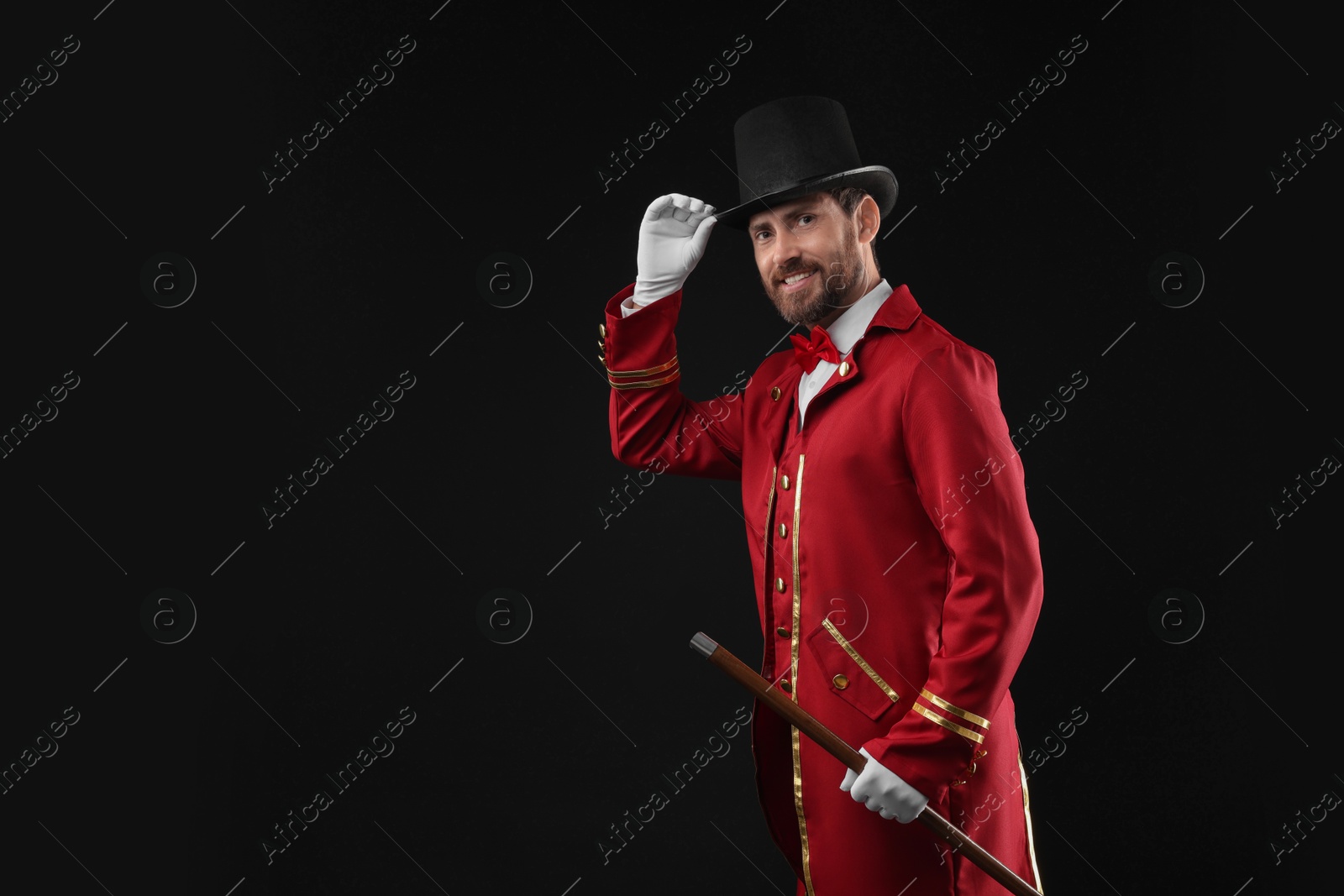 Photo of Portrait of showman in red costume and hat on black background, space for text