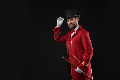 Photo of Portrait of showman in red costume and hat on black background, space for text