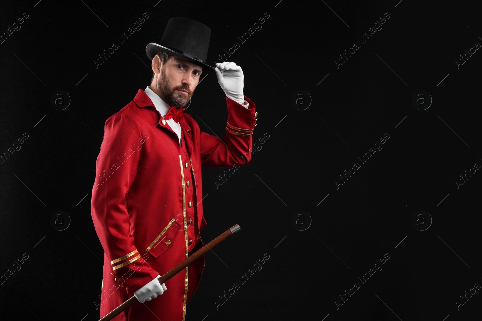 Photo of Portrait of showman in red costume and hat on black background, space for text