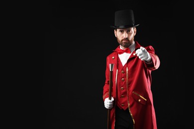 Photo of Portrait of showman in red costume and hat on black background, space for text