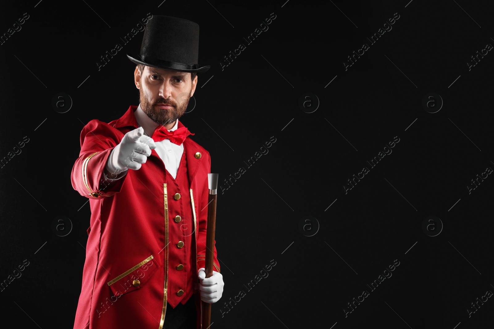 Photo of Portrait of showman in red costume and hat on black background, space for text