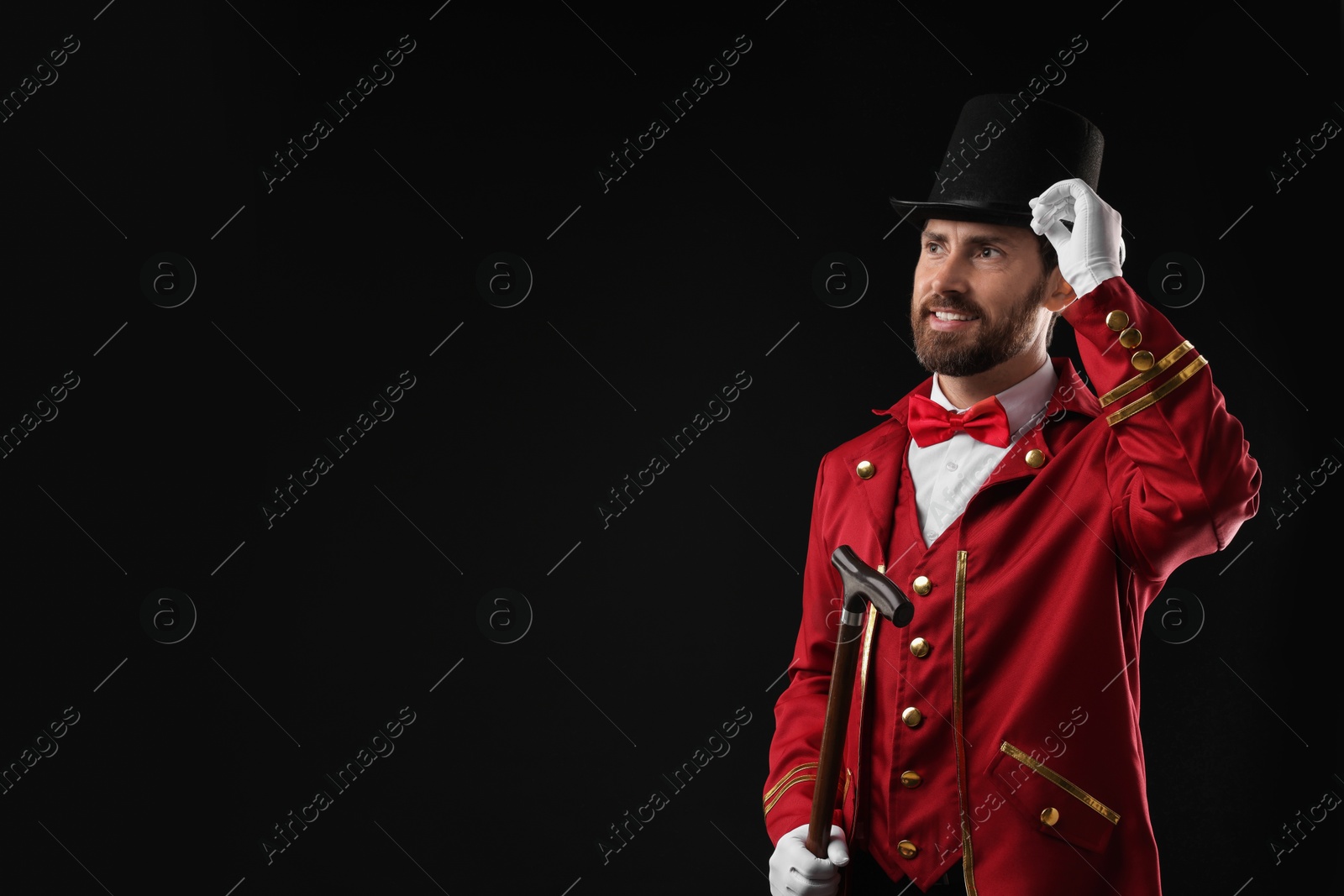 Photo of Portrait of showman in red costume and hat on black background, space for text