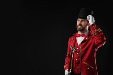 Photo of Portrait of showman in red costume and hat on black background, space for text