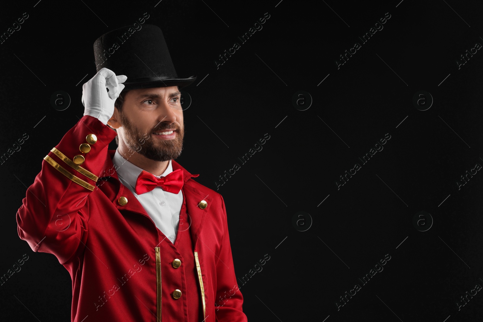 Photo of Portrait of showman in red costume and hat on black background, space for text