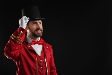 Photo of Portrait of showman in red costume and hat on black background, space for text