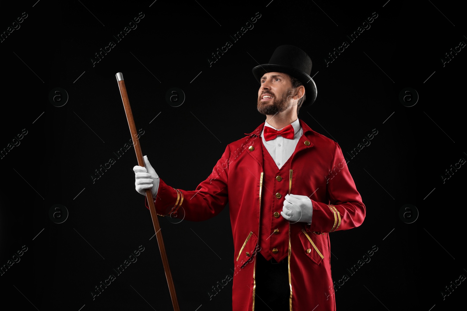 Photo of Portrait of showman in red costume and hat on black background