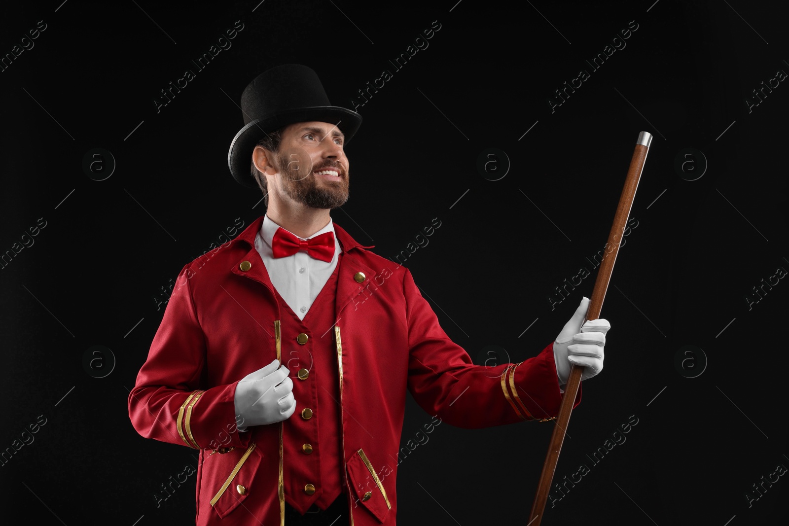 Photo of Portrait of showman in red costume and hat on black background