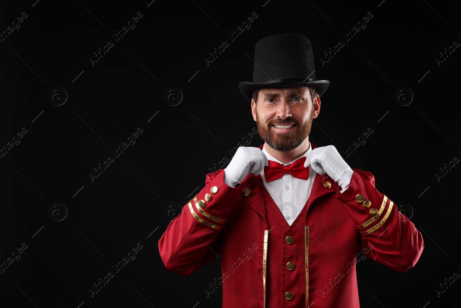 Photo of Portrait of showman in red costume and hat on black background