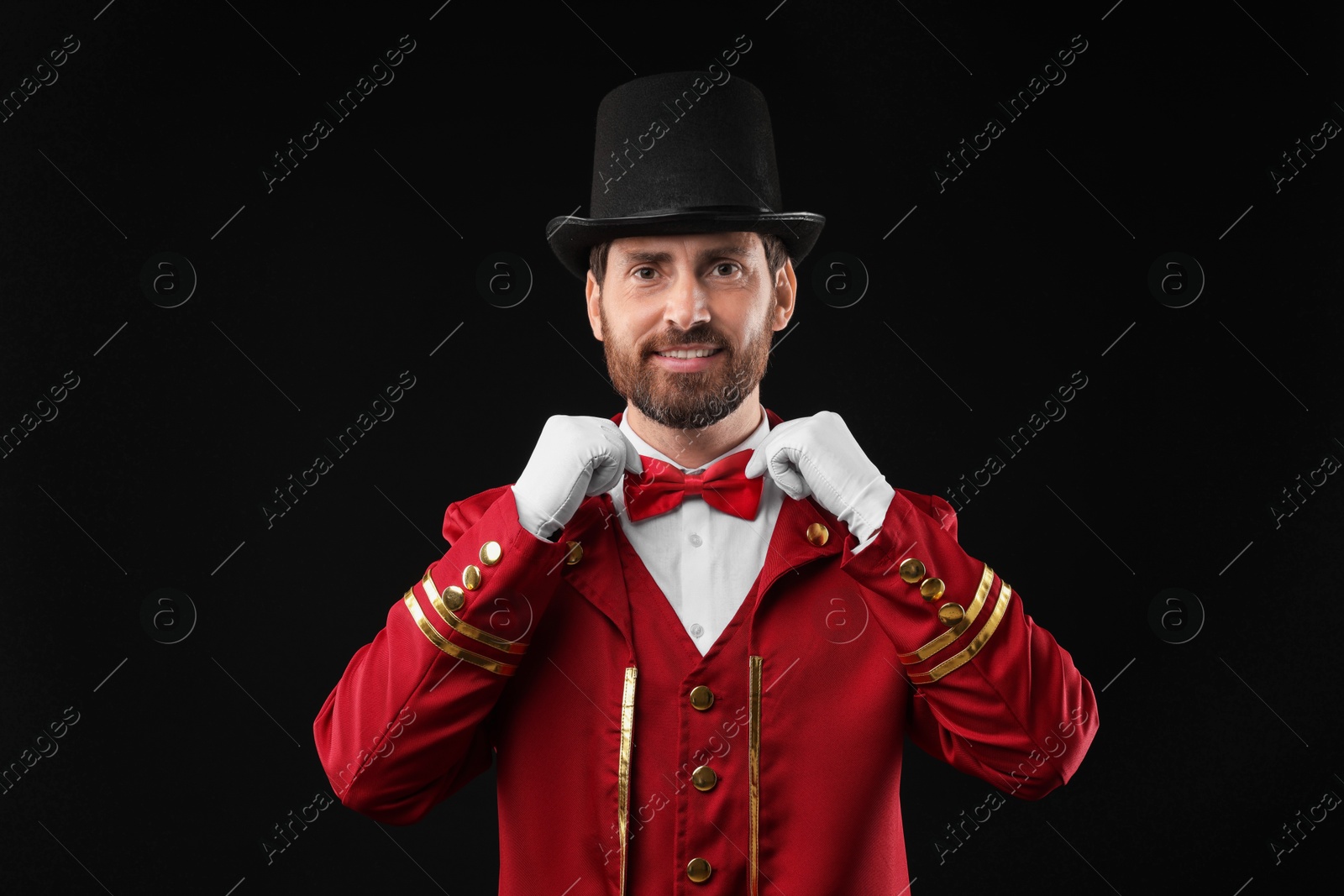 Photo of Portrait of showman in red costume and hat on black background