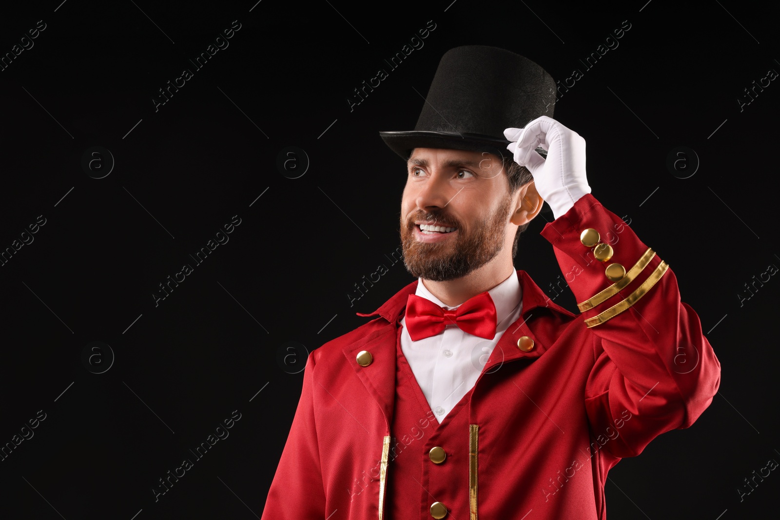 Photo of Portrait of showman in red costume and hat on black background, space for text