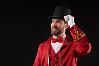 Photo of Portrait of showman in red costume and hat on black background, space for text