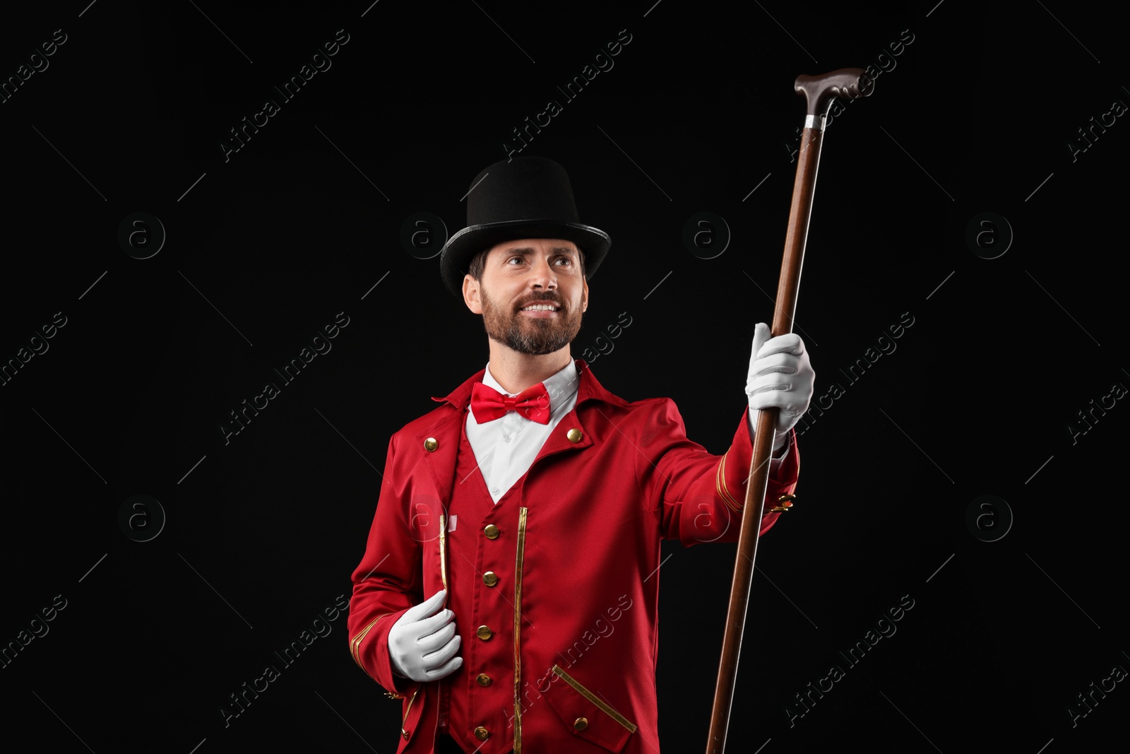 Photo of Portrait of showman in red costume and hat on black background