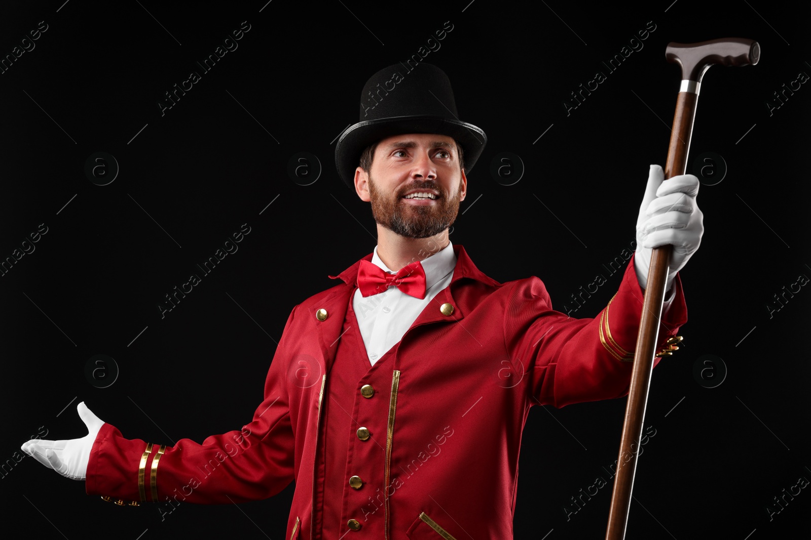 Photo of Portrait of showman in red costume and hat on black background