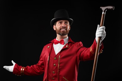 Photo of Portrait of showman in red costume and hat on black background