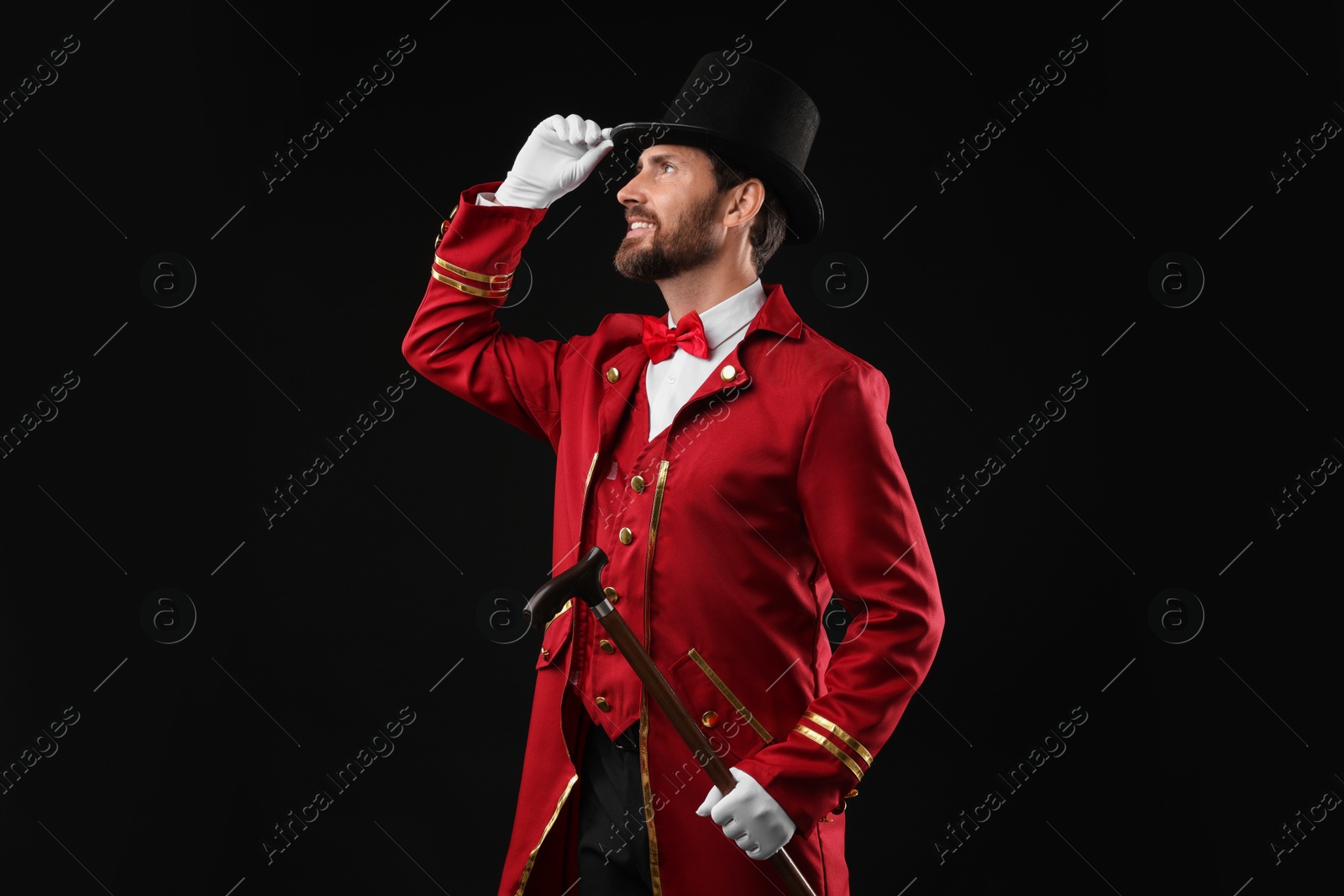 Photo of Portrait of showman in red costume and hat on black background