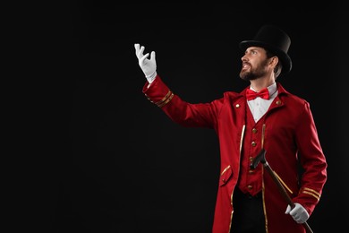 Photo of Portrait of showman in red costume and hat on black background, space for text