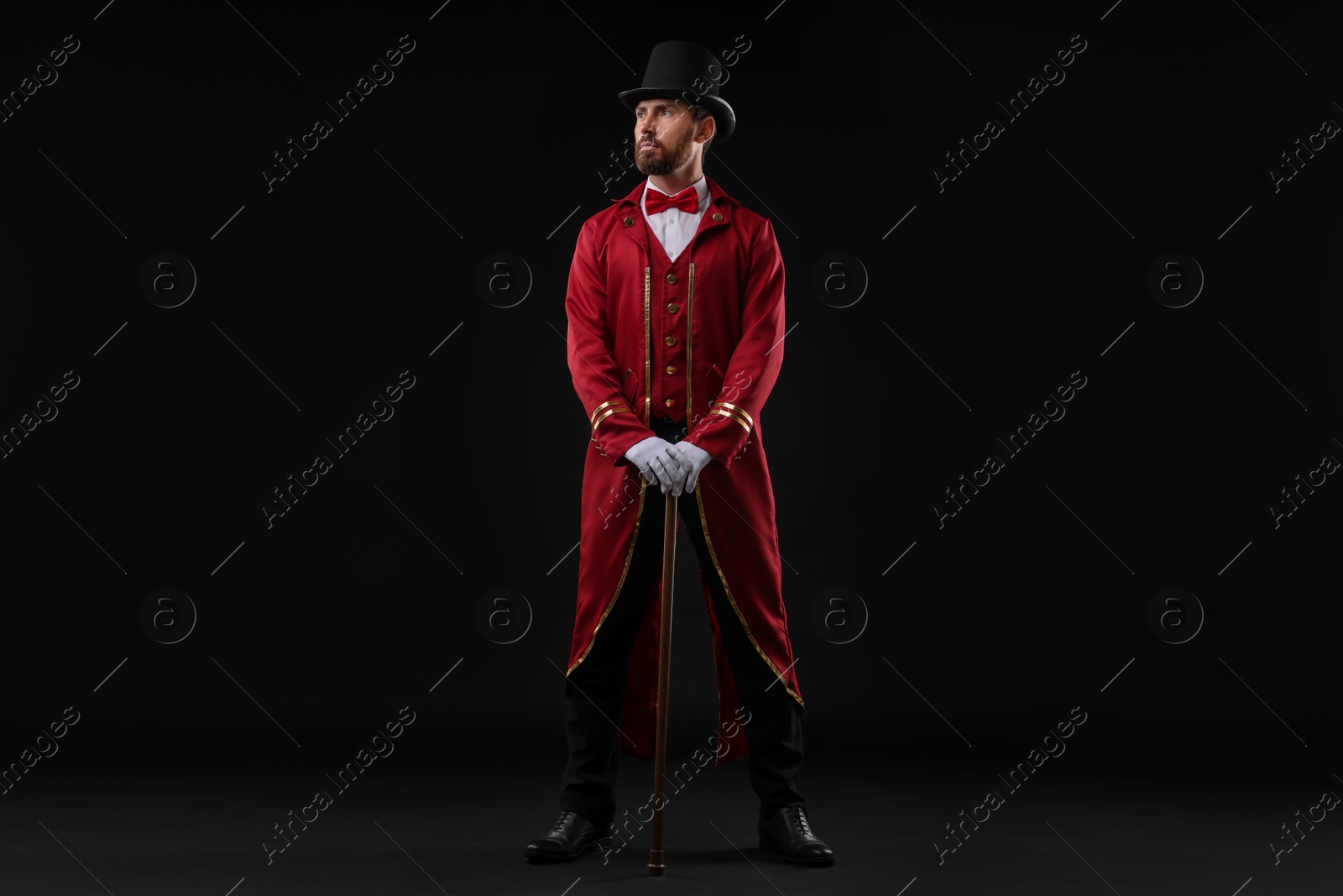 Photo of Portrait of showman in red costume and hat on black background