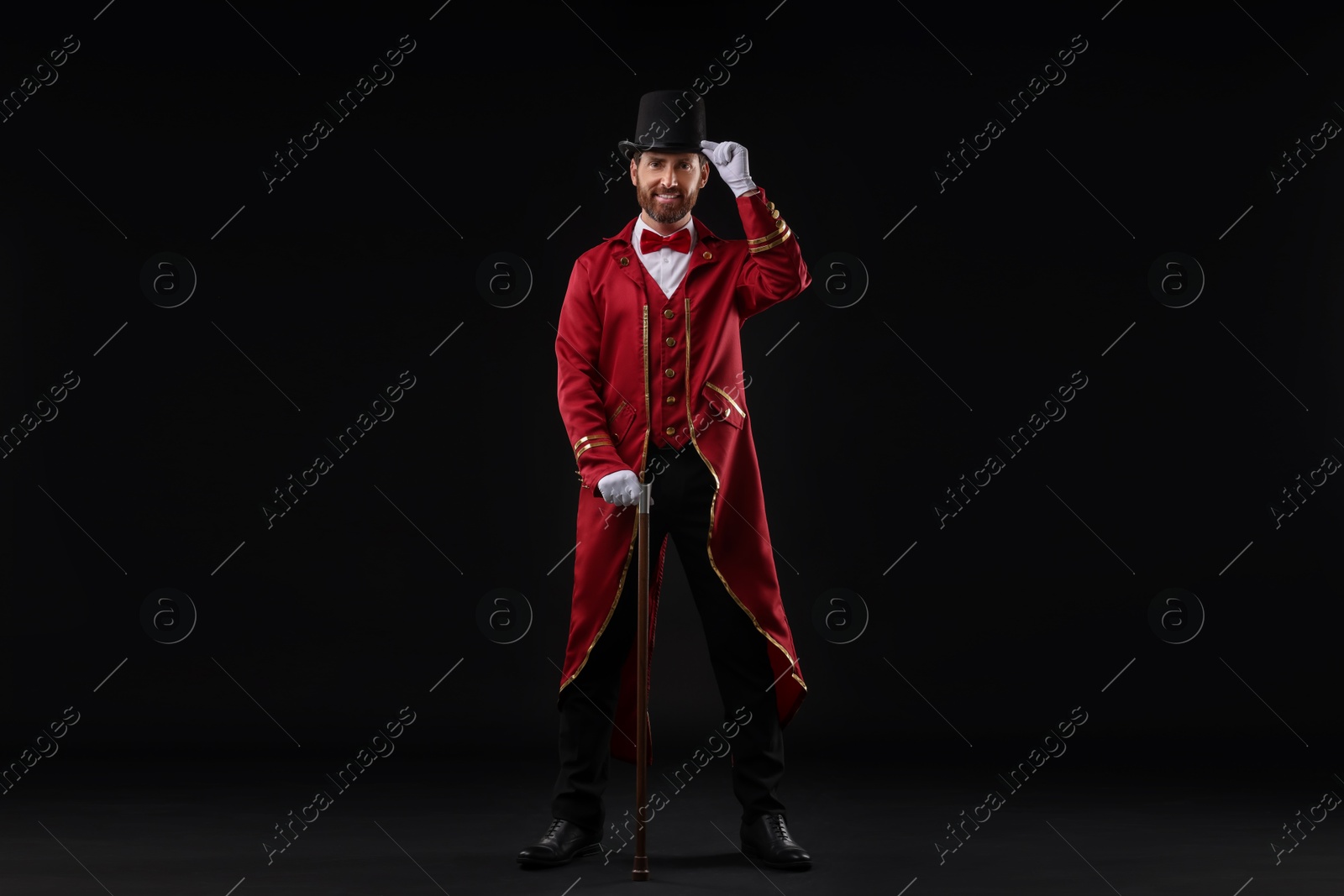 Photo of Portrait of showman in red costume and hat on black background