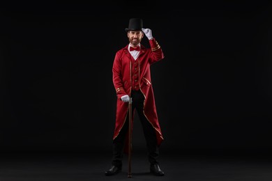 Photo of Portrait of showman in red costume and hat on black background