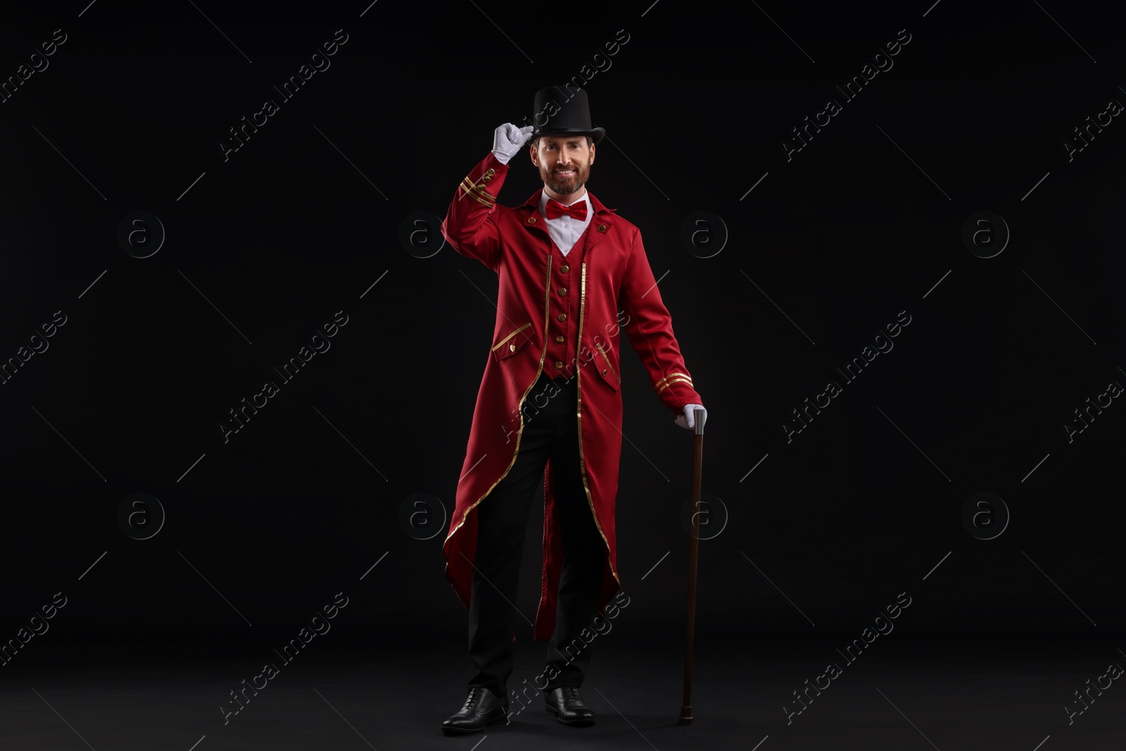 Photo of Portrait of showman in red costume and hat on black background