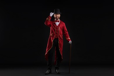 Photo of Portrait of showman in red costume and hat on black background