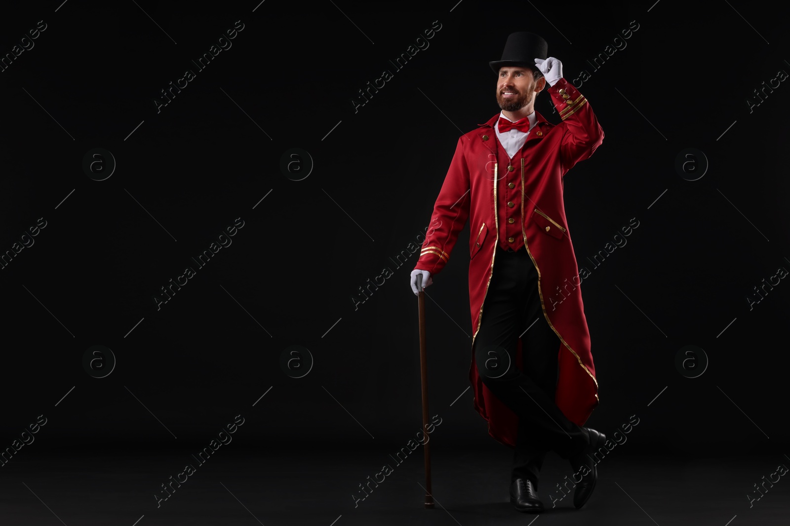 Photo of Portrait of showman in red costume and hat on black background, space for text