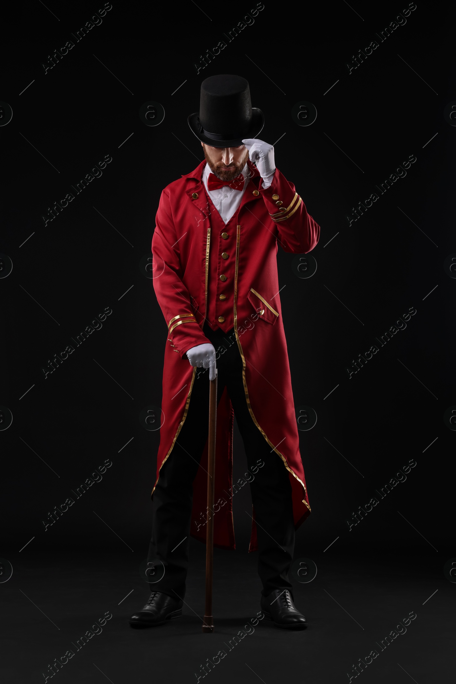 Photo of Portrait of showman in red costume and hat on black background