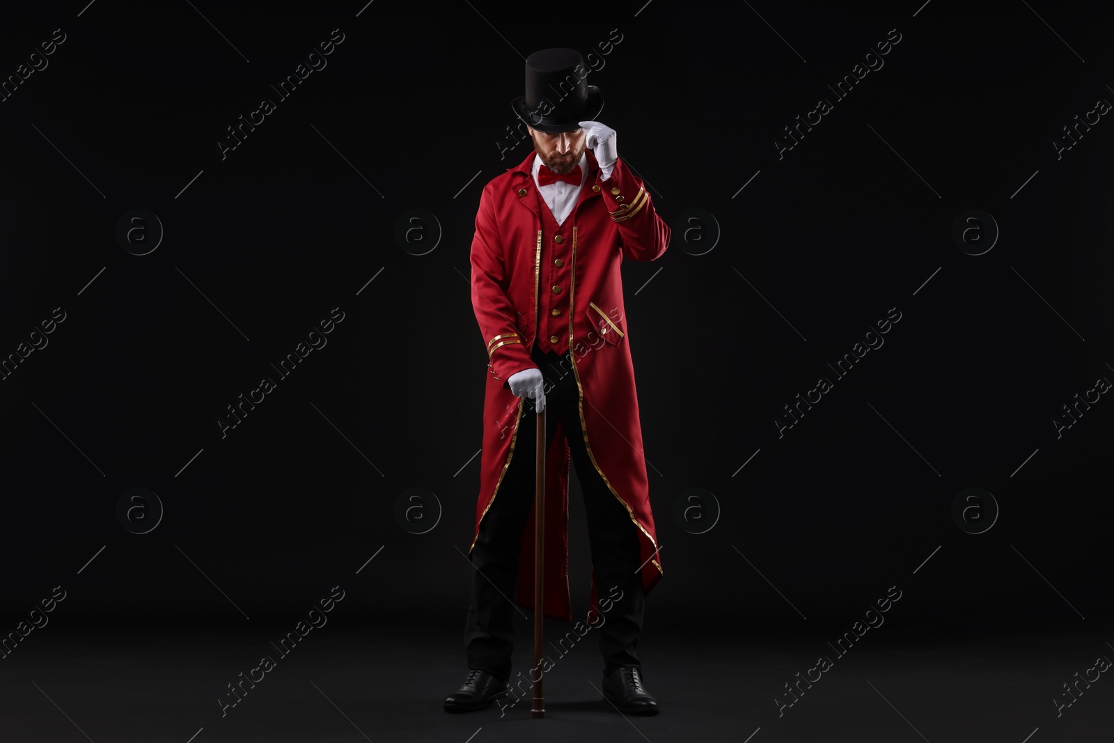 Photo of Portrait of showman in red costume and hat on black background