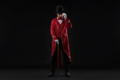 Photo of Portrait of showman in red costume and hat on black background