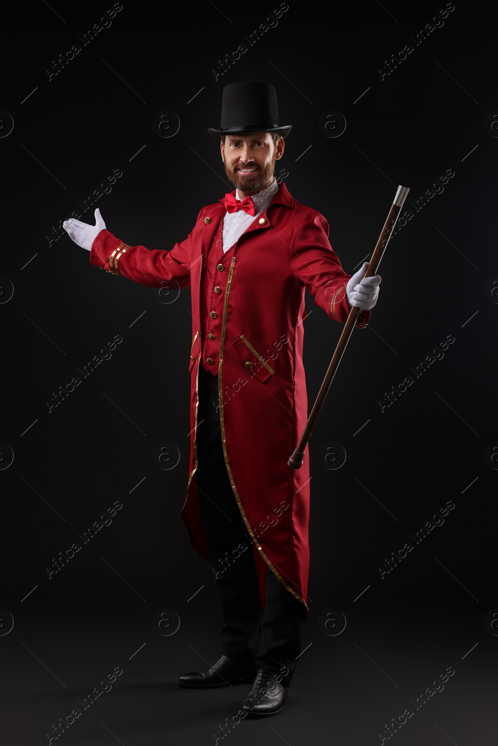 Photo of Portrait of showman in red costume and hat on black background