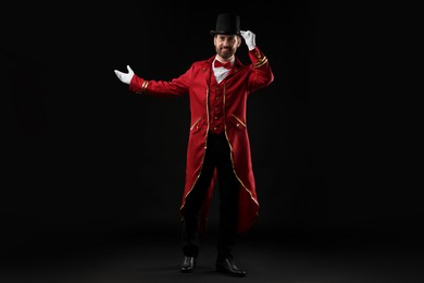 Photo of Portrait of showman in red costume and hat on black background