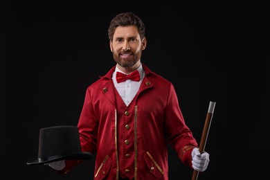 Portrait of showman in red costume and hat on black background