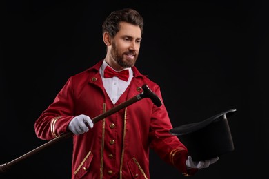 Photo of Portrait of showman in red costume and hat on black background