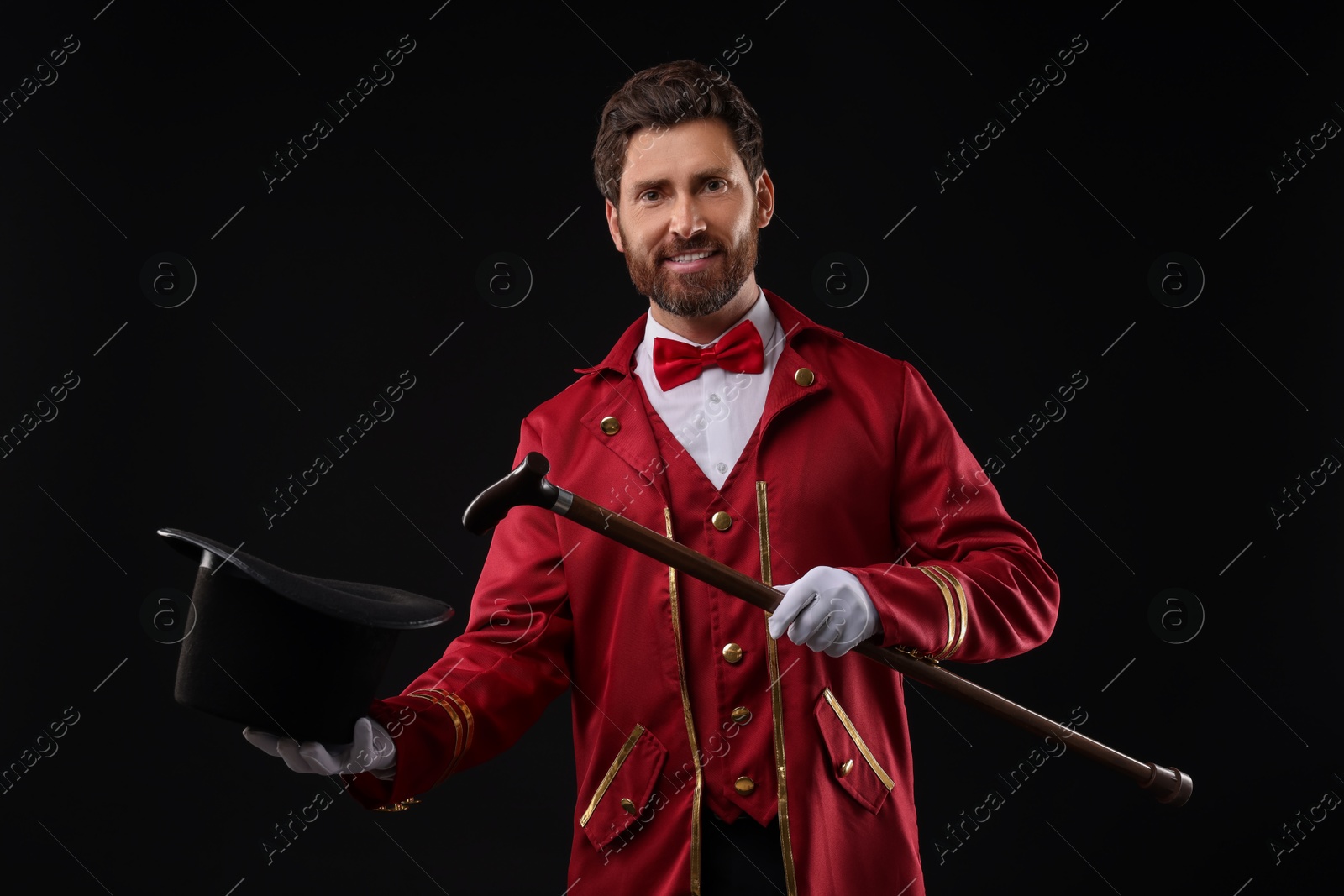 Photo of Portrait of showman in red costume and hat on black background