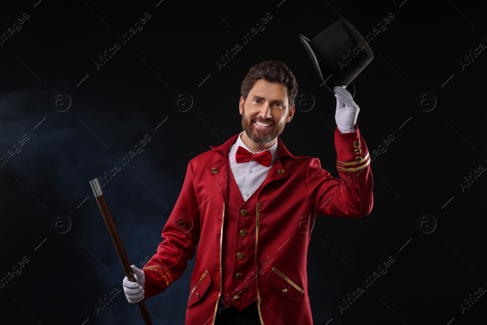 Photo of Portrait of showman in red costume and hat on black background