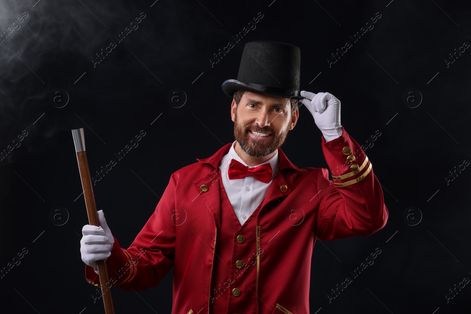 Photo of Portrait of showman in red costume and hat on black background