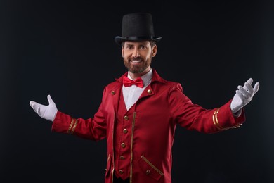 Portrait of showman in red costume and hat on black background