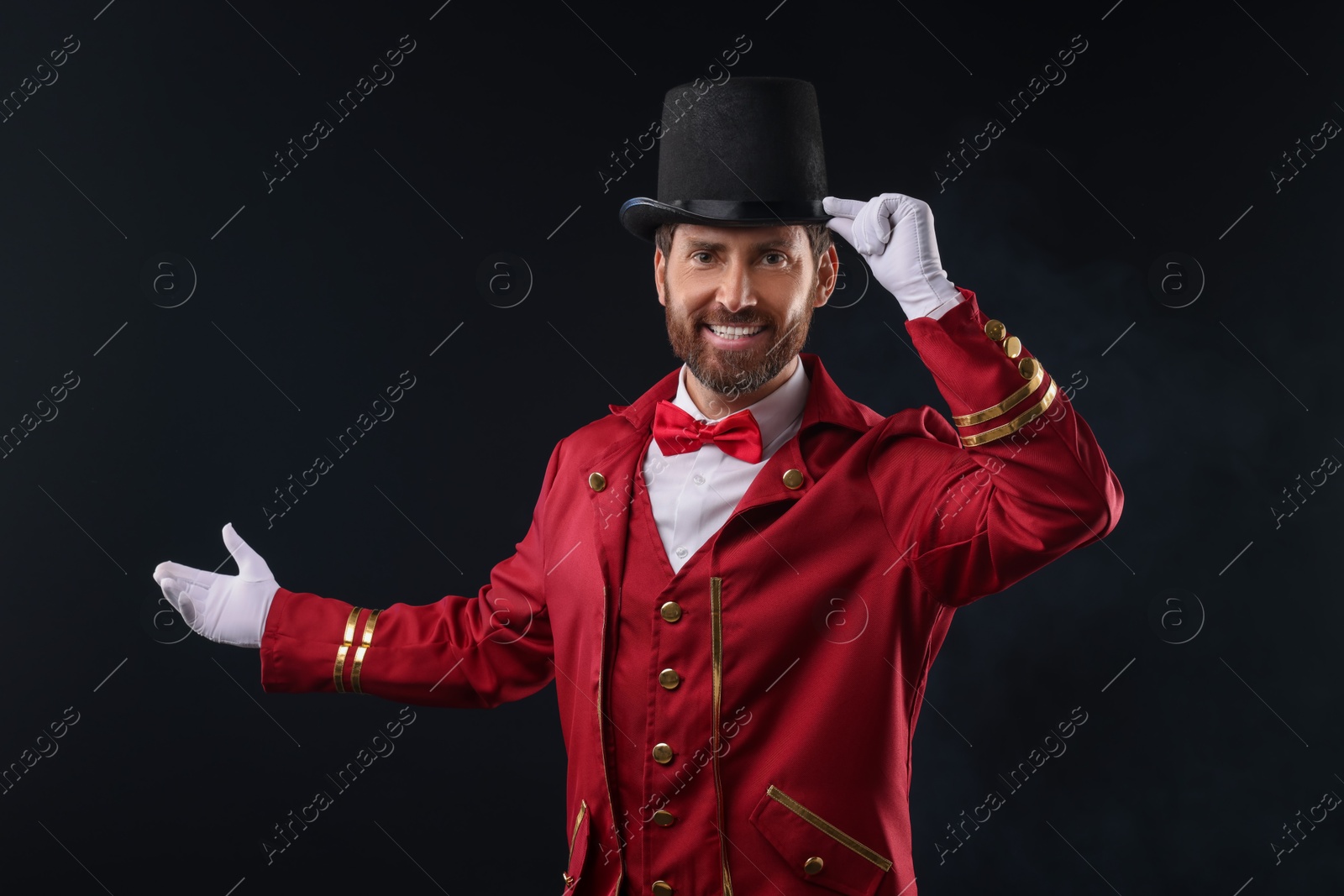 Photo of Portrait of showman in red costume and hat on black background