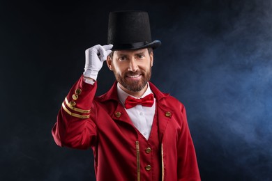 Photo of Portrait of showman in red costume and hat on black background with smoke