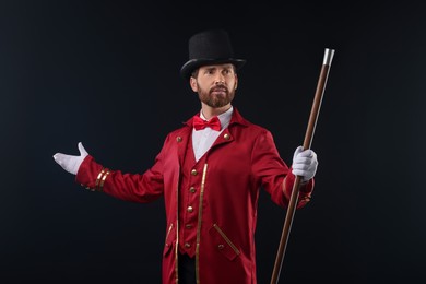 Photo of Portrait of showman in red costume and hat on black background with smoke