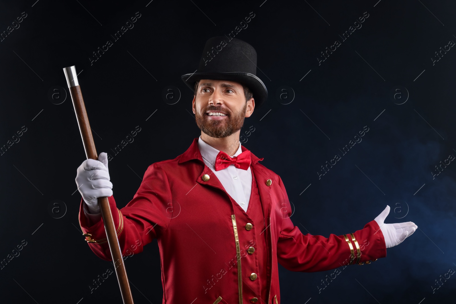 Photo of Portrait of showman in red costume and hat on black background with smoke