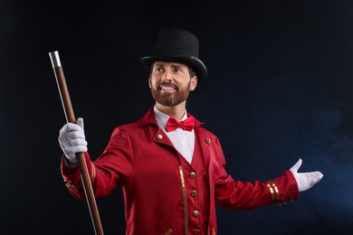 Photo of Portrait of showman in red costume and hat on black background with smoke