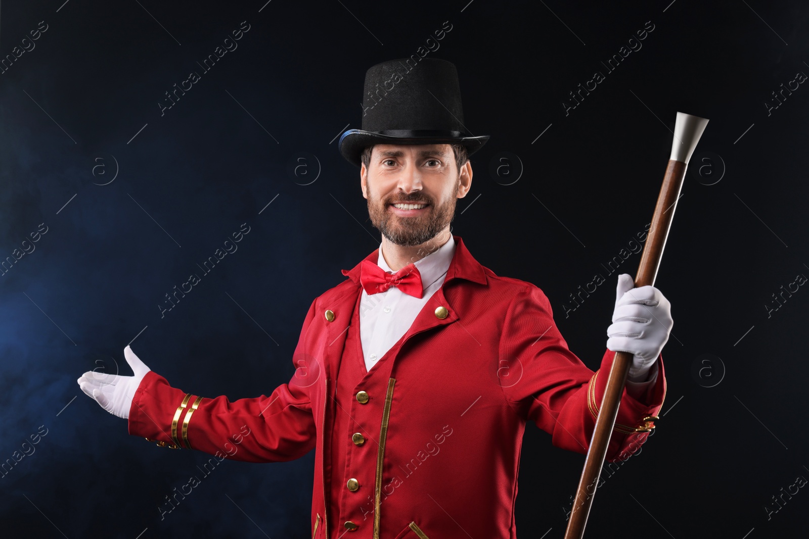 Photo of Portrait of showman in red costume and hat on black background with smoke