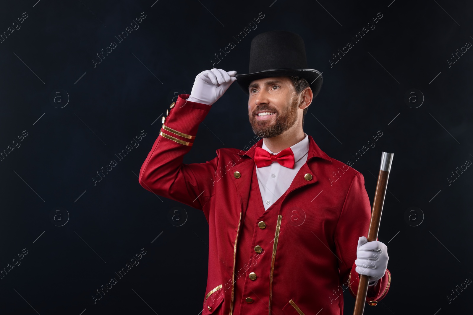 Photo of Portrait of showman in red costume and hat on black background with smoke