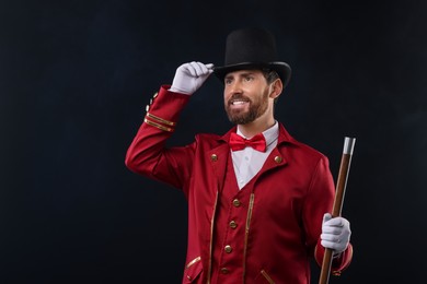 Photo of Portrait of showman in red costume and hat on black background with smoke